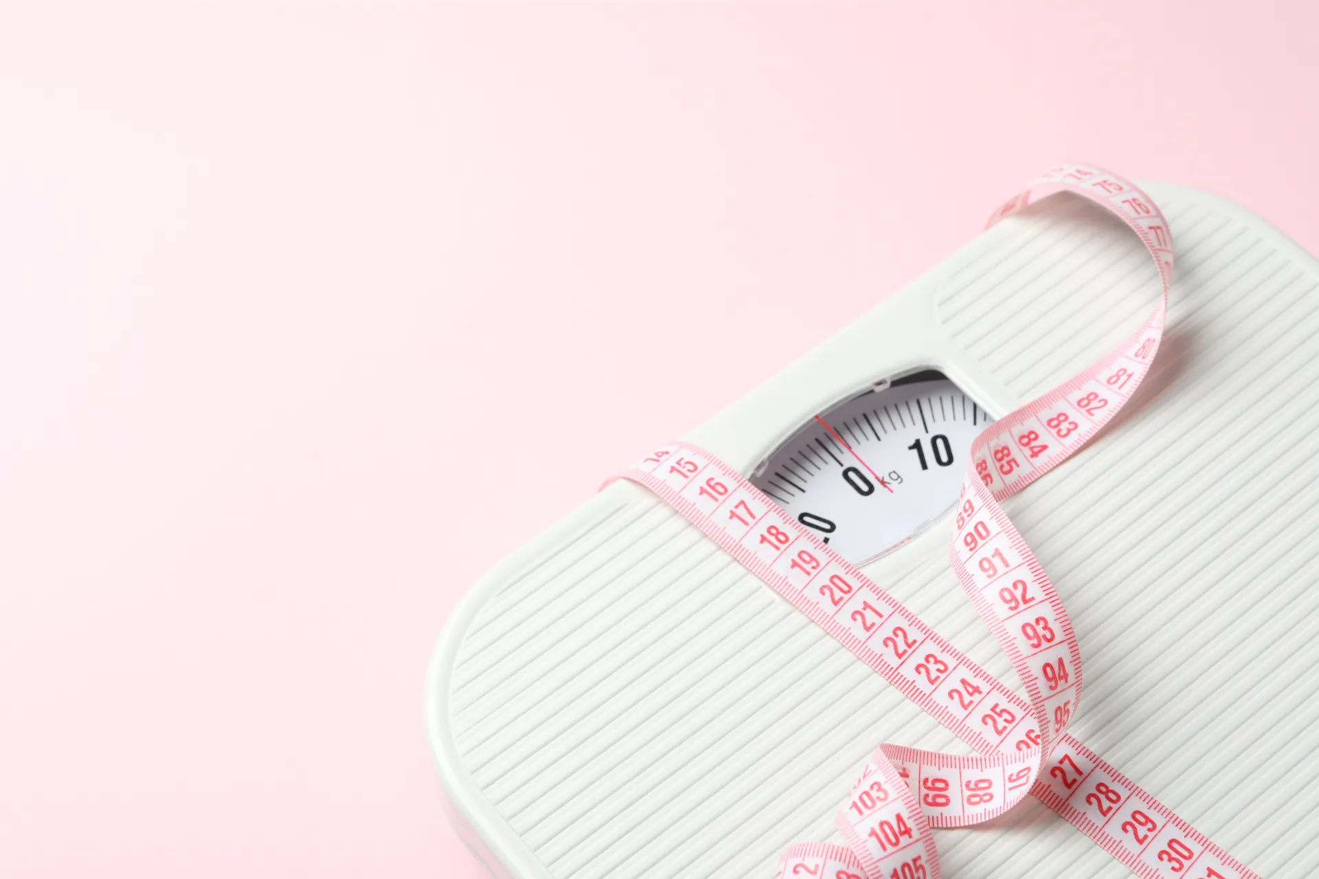 bathroom scale with measuring tape on pink backgro utc