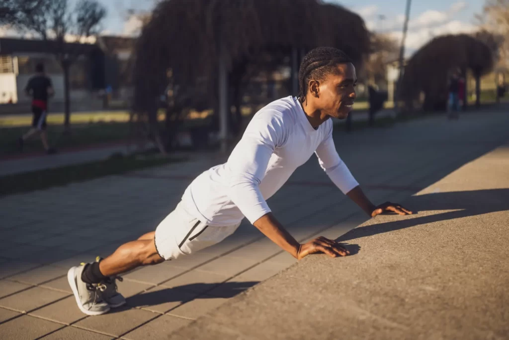 man doing push ups outdoors in city environment utc