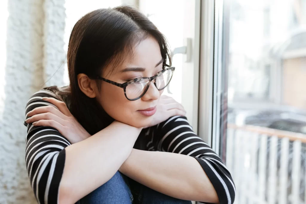 pensive asian woman in sweater and eyeglasses whic utc