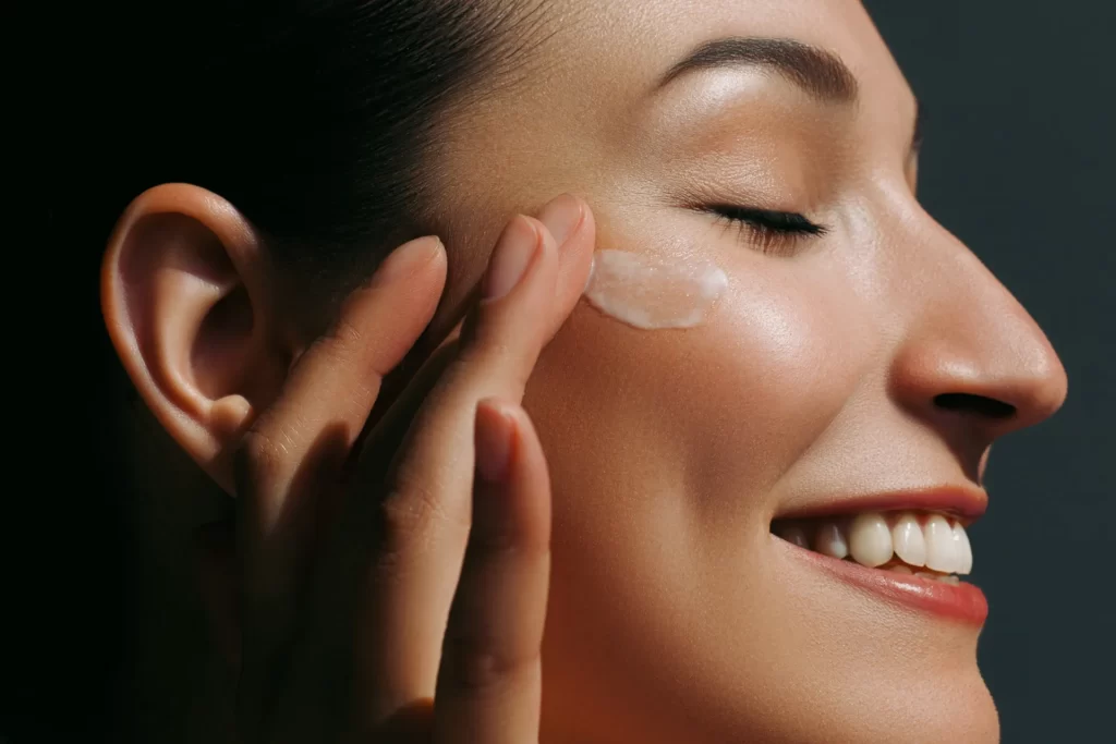 smiling woman applying cream to her face utc