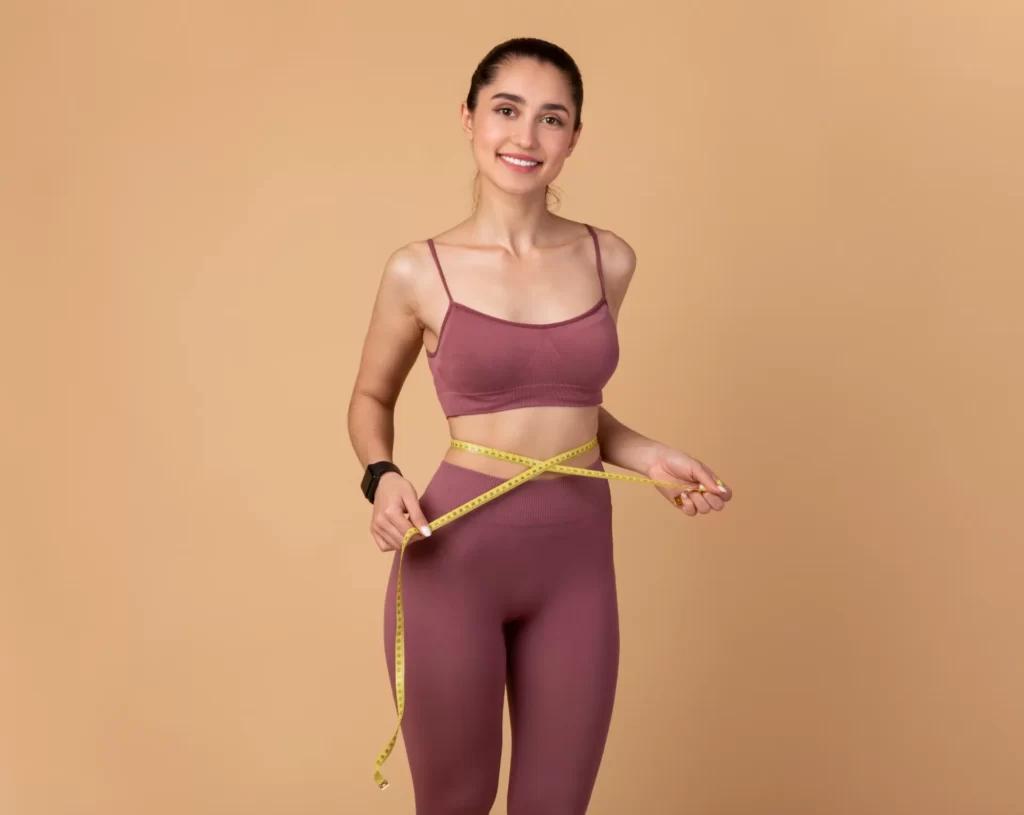 woman measures waist with tape measure in studio utc ()