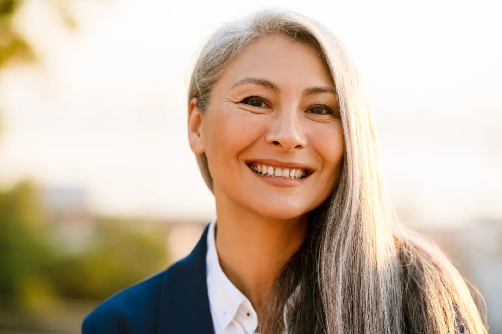 smiling woman with grey hair wearing blazer utc